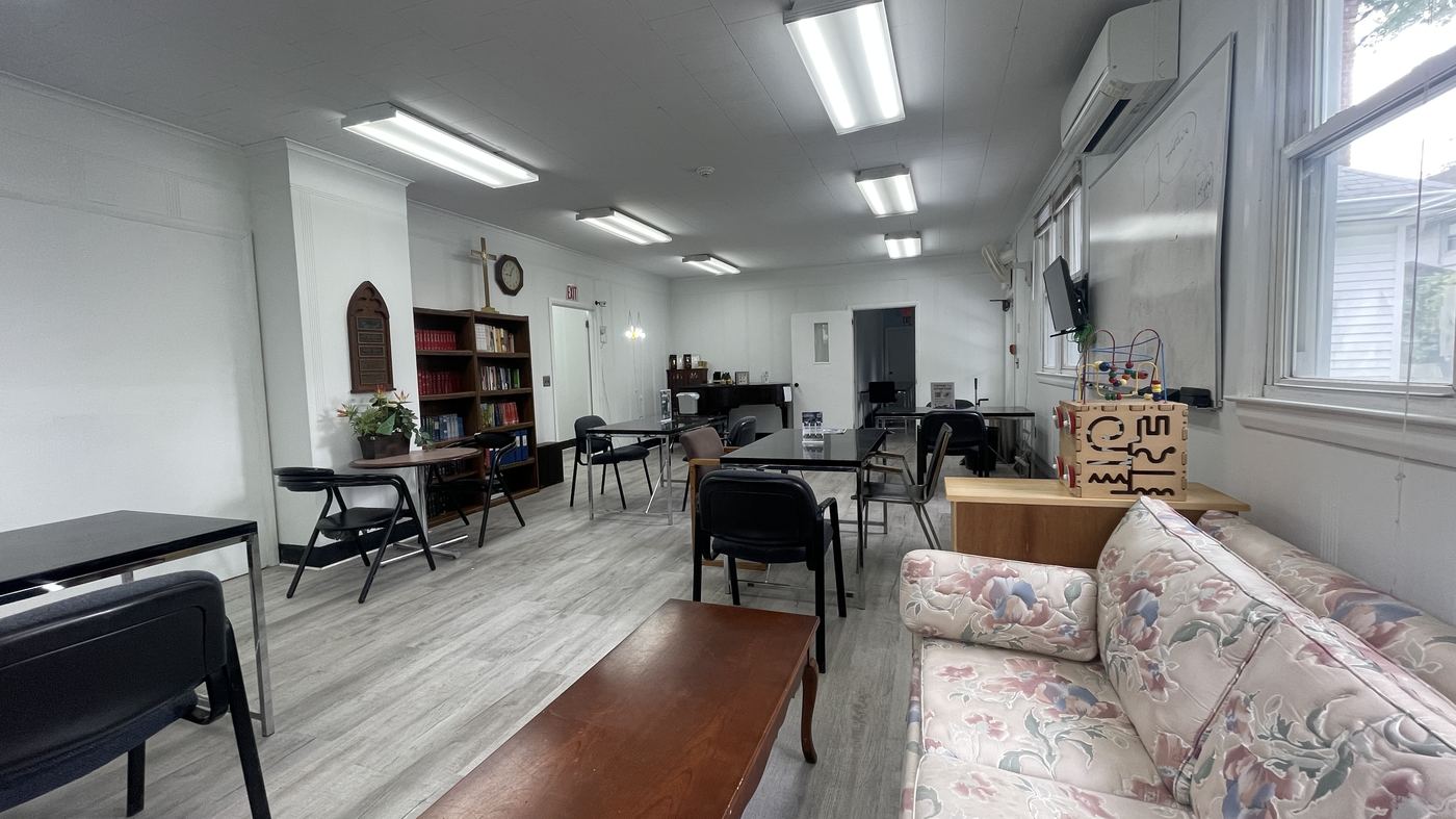 Fellowship hall with tables, bookshelves, and a cross